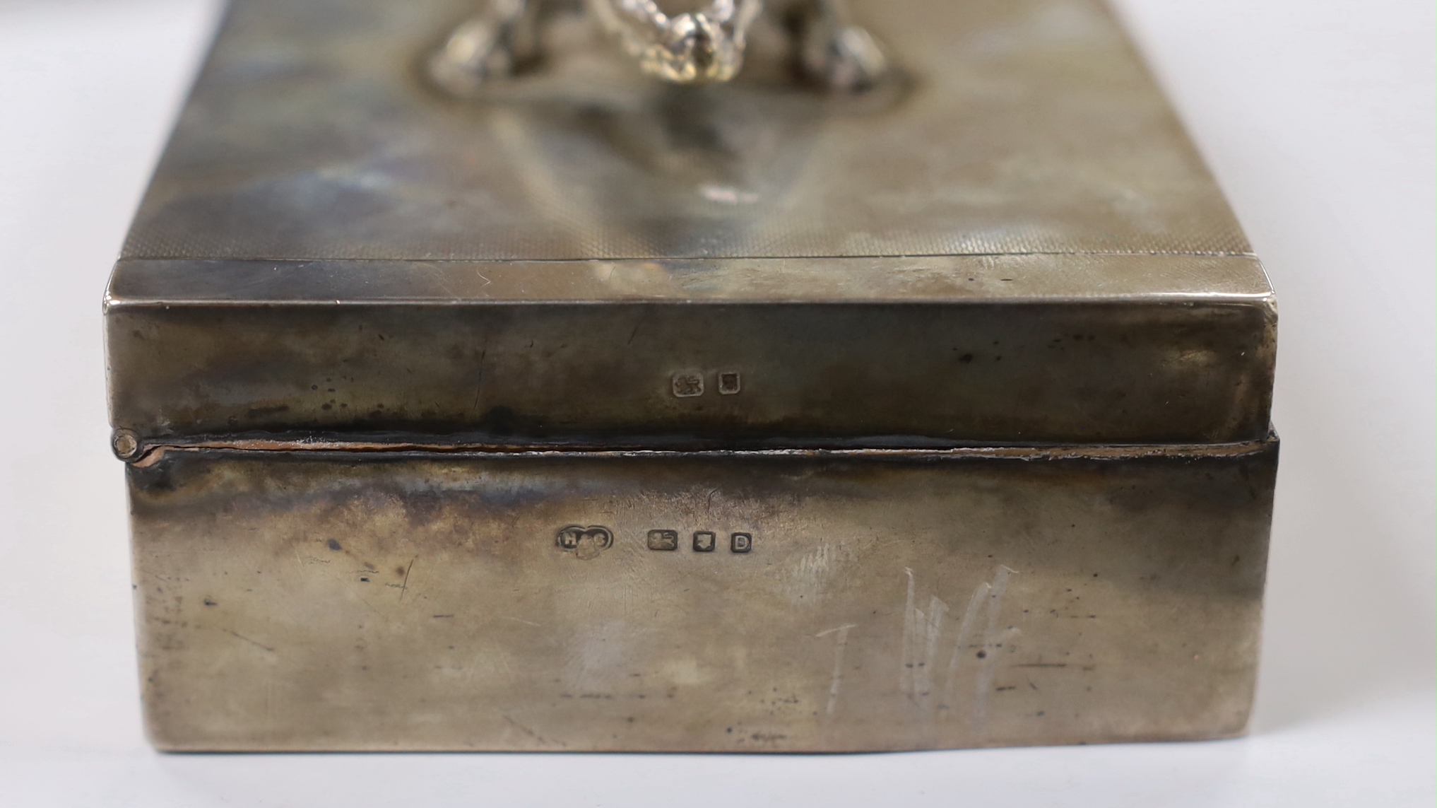 A George VI part engine tuned silver mounted rectangular cigarette box, with white metal crocodile surmount and interior presentation inscription relating to 'Lt. Colonel K.F.G. Stronach', maker Hamilton & Co, London, 19